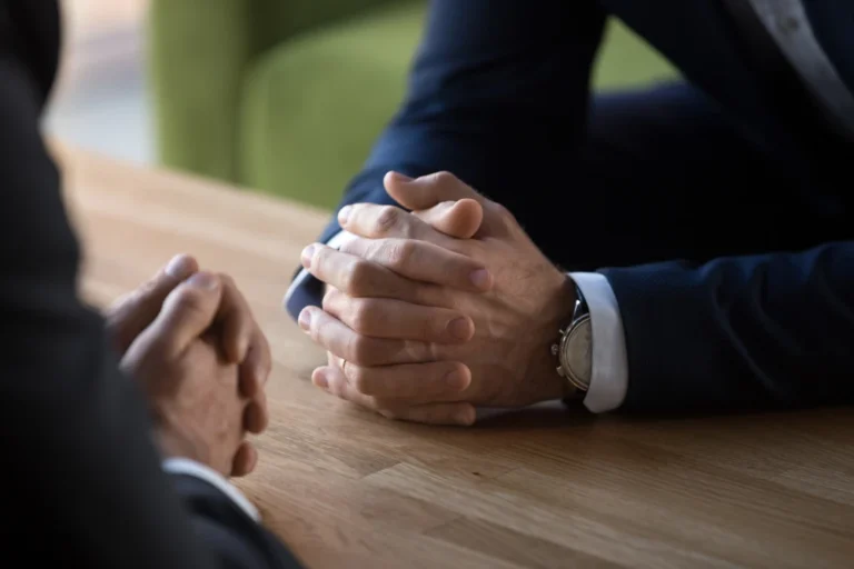 Close-up of clasped hands during business negotiation meeting.