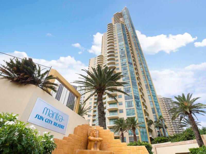 Mantra Sun City Resort high-rise on Gold Coast QLD with palm trees and golden statue at entrance